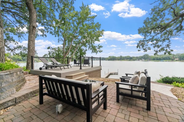 Outdoor seating area by a lake with lounge chairs and a wooden dock.