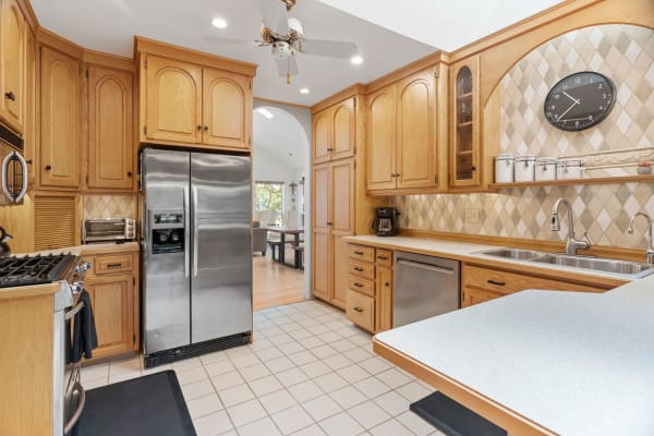 Interior view of a modern kitchen with wooden cabinets and stainless steel refrigerator.