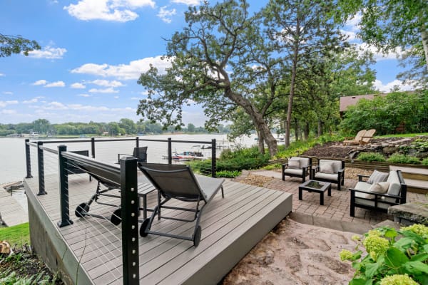 A serene lakeside deck with outdoor furniture and a picturesque view of the water.