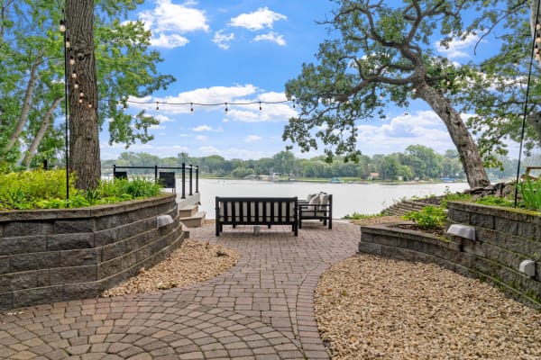 Serene lakeside view with a bench, sofa, and decorative string lights.