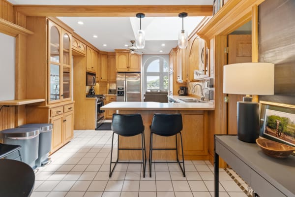 A cozy kitchen with wooden cabinets, an island, and stylish bar stools.