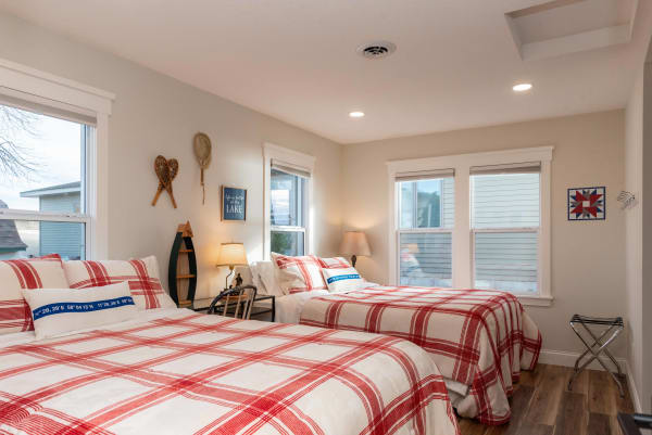 A cozy bedroom featuring two beds with red and white plaid quilts and rustic decorations.