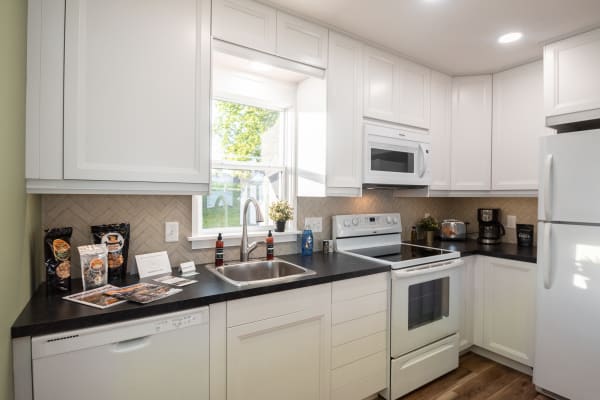 Modern kitchen featuring white cabinetry, dark countertop, and a charming window.