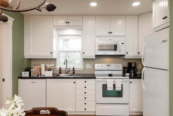 Modern kitchen with white cabinets, dark countertops, and a window offering natural light.