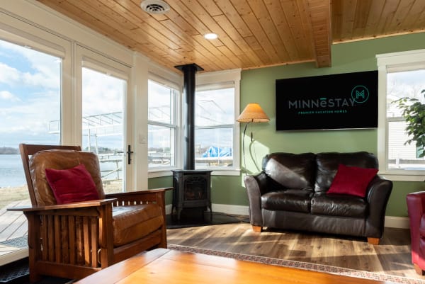 Cozy living room with wooden ceiling, leather furniture, and large windows overlooking water.