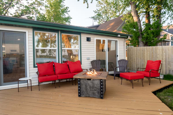 An inviting outdoor space with red cushioned furniture and a fire pit on a wooden deck.