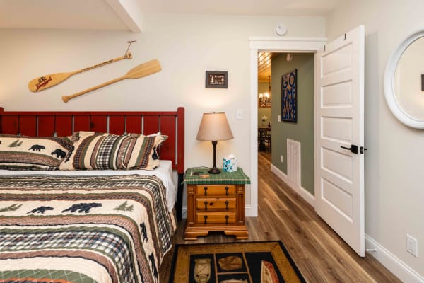 Cozy cabin-style bedroom with wooden bed, plaid quilt, and rustic decor.