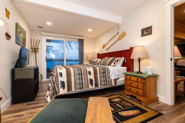 Cozy bedroom featuring a patterned quilt, wooden accents, and a view of the water.