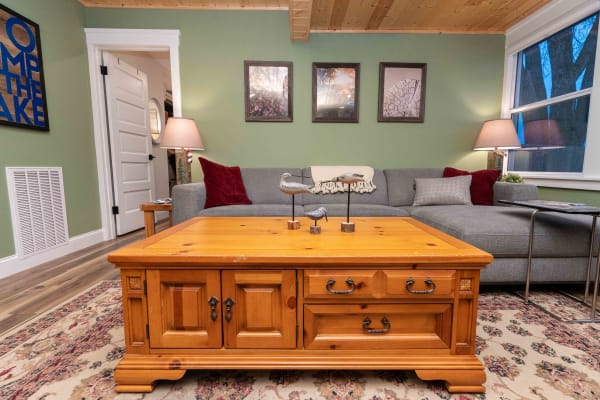 A cozy living room with a wooden coffee table, gray sectional sofa, and framed nature photographs.