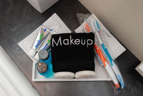 Toiletries organized on a countertop including a towel labeled 'Makeup', toothpaste, toothbrushes, and small bottles.