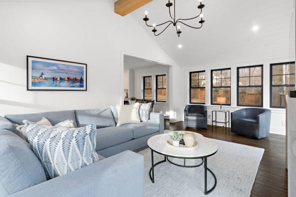 Modern living room with light blue sofa, art on the wall, and large windows.