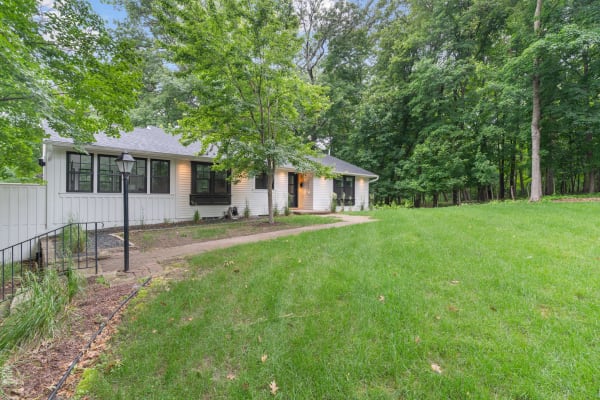 A single-story house with a green lawn and trees.