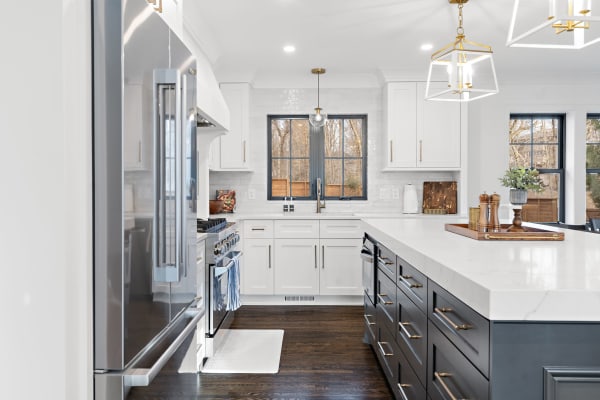 Stylish kitchen with a white marble island, navy cabinets, stainless steel appliances, and natural light.