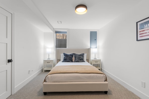 Modern bedroom featuring a beige bed with decorative pillows and nightstands.