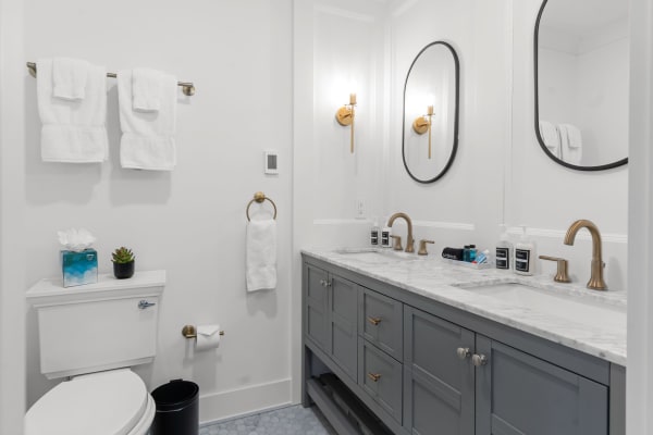 Modern bathroom with a white and grey color scheme, featuring a marble countertop and gold fixtures.