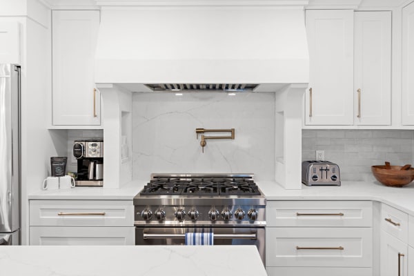 Sleek kitchen with a stainless steel oven, white cabinets, and marble backsplash.