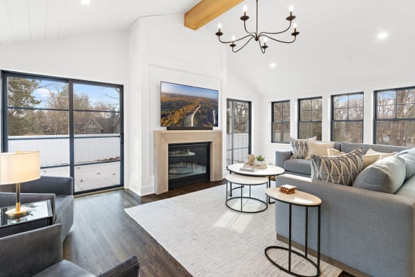 A bright living room featuring a gray sectional sofa, a fireplace, and large windows.