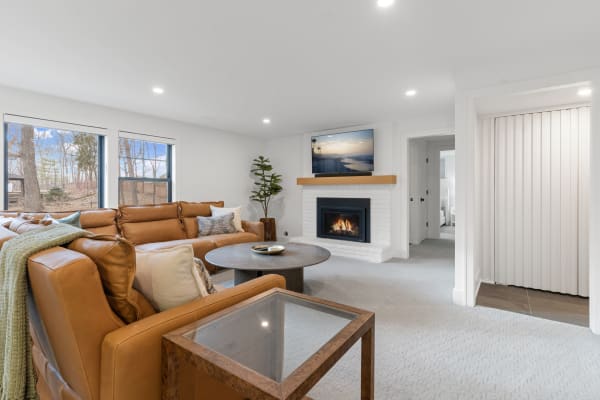 A modern living room featuring a leather sectional sofa, a fireplace, and large windows with natural light.
