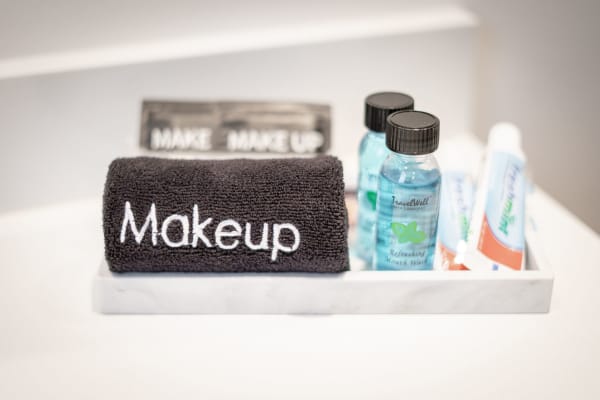 A bathroom tray with a black towel labeled 'Makeup', bottles of mouthwash, and toothpaste tubes.