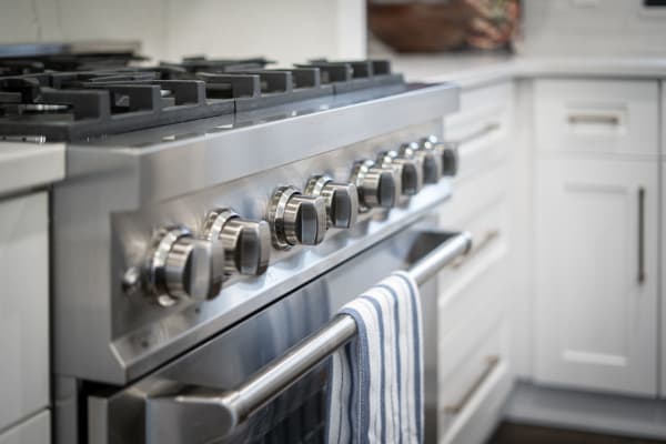 Close-up of a stainless-steel gas stove with control knobs and a hanging towel.