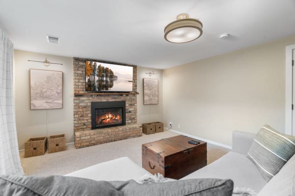 Cozy basement living space with a fireplace, wooden chest, and artistic decor.