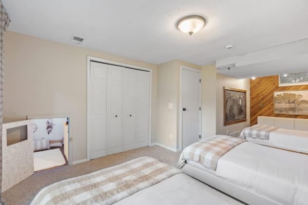 A bedroom with two beds, a closet, wooden accents, and a play area.