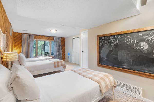 Room with three beds, a chalkboard, and warm wooden accents.