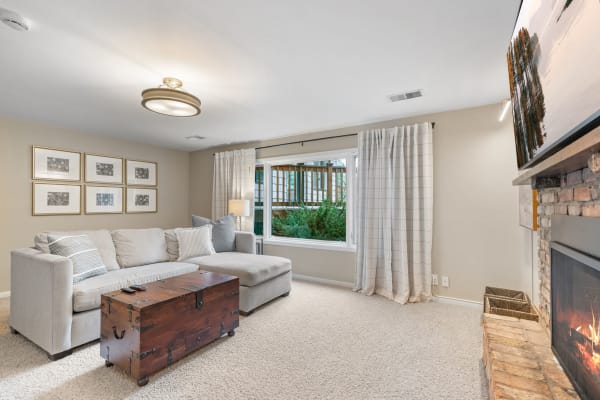 Cozy living room with a gray sectional sofa, wooden coffee table, and stone fireplace.