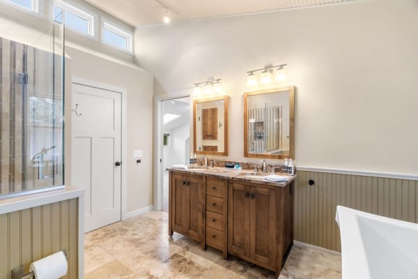 A contemporary bathroom featuring a wooden vanity, dual sinks, and a glass-enclosed shower.