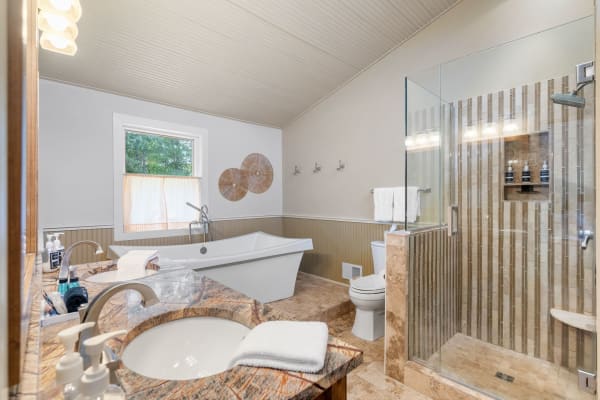 A spacious modern bathroom with a freestanding tub, glass shower, and stylish decor.