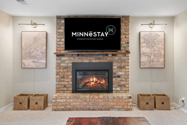 Cozy living area with a brick fireplace, TV, and framed sketches.