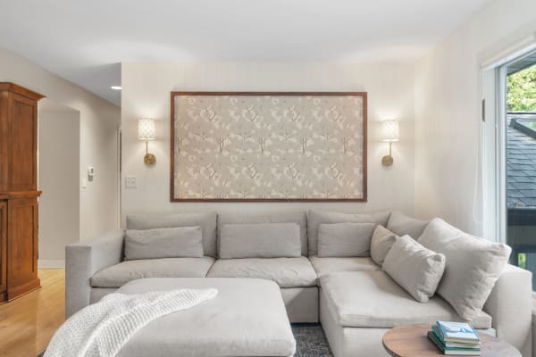 A modern living room with a sectional couch, wall art, and decorative lighting.