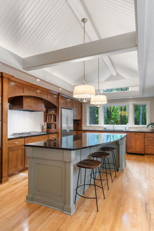 A modern kitchen featuring a vaulted ceiling, wooden cabinets, and a granite island.
