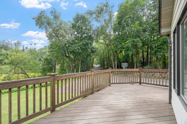 Wooden deck view with trees and a basketball hoop in the background.