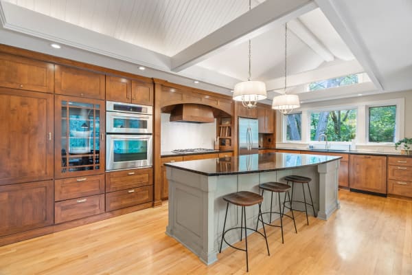A modern kitchen with dark wood cabinets, a granite island, and large windows.