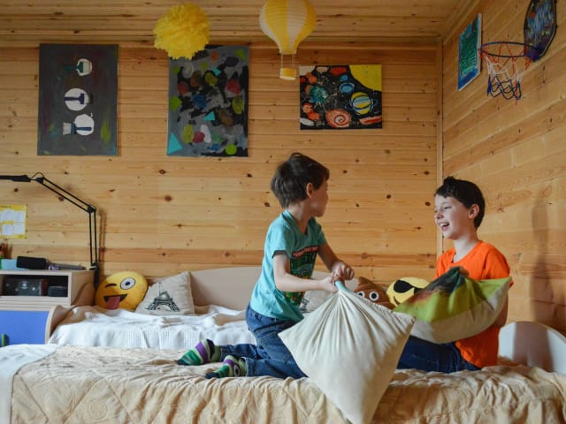 Two kids laughing during a playful pillow fight