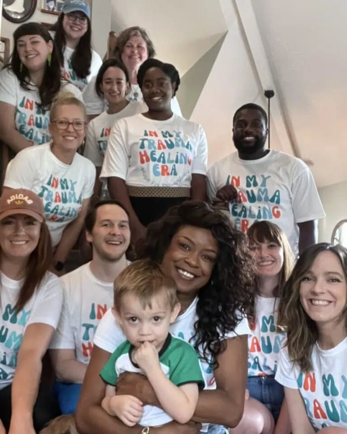 Hope For The Journey Collective staff on a staircase wearing matching In My Trauma Healing Era t-shirts