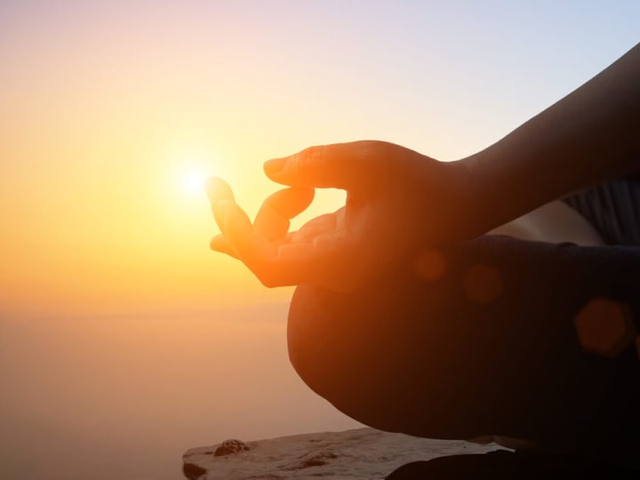 A person meditating at sunrise