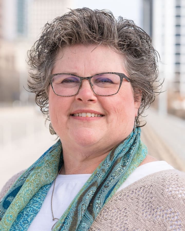 Heather Hammock smiling outdoors in glasses and a colorful scarf