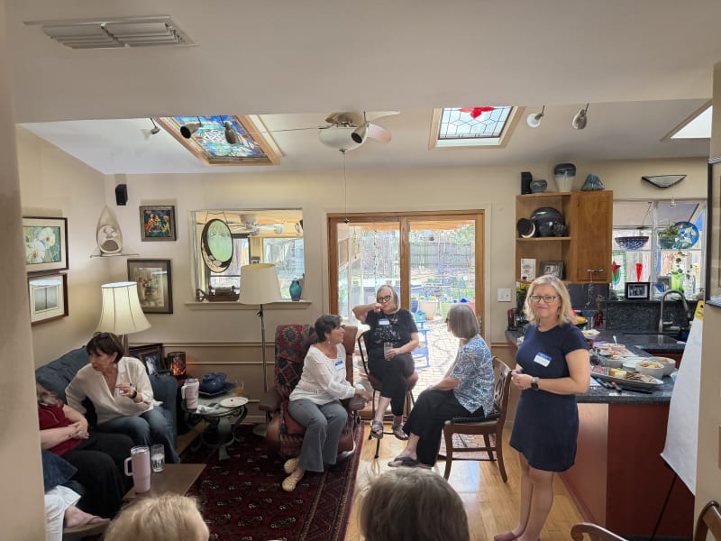 Women gathered in a sunlit living room at a Gatherings For Good event