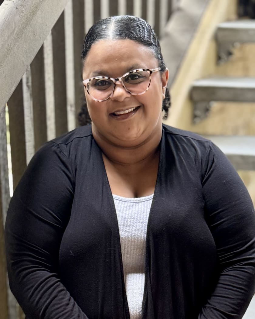 Ivana Crumpton, LPC-Associate, smiling on a wooden staircase