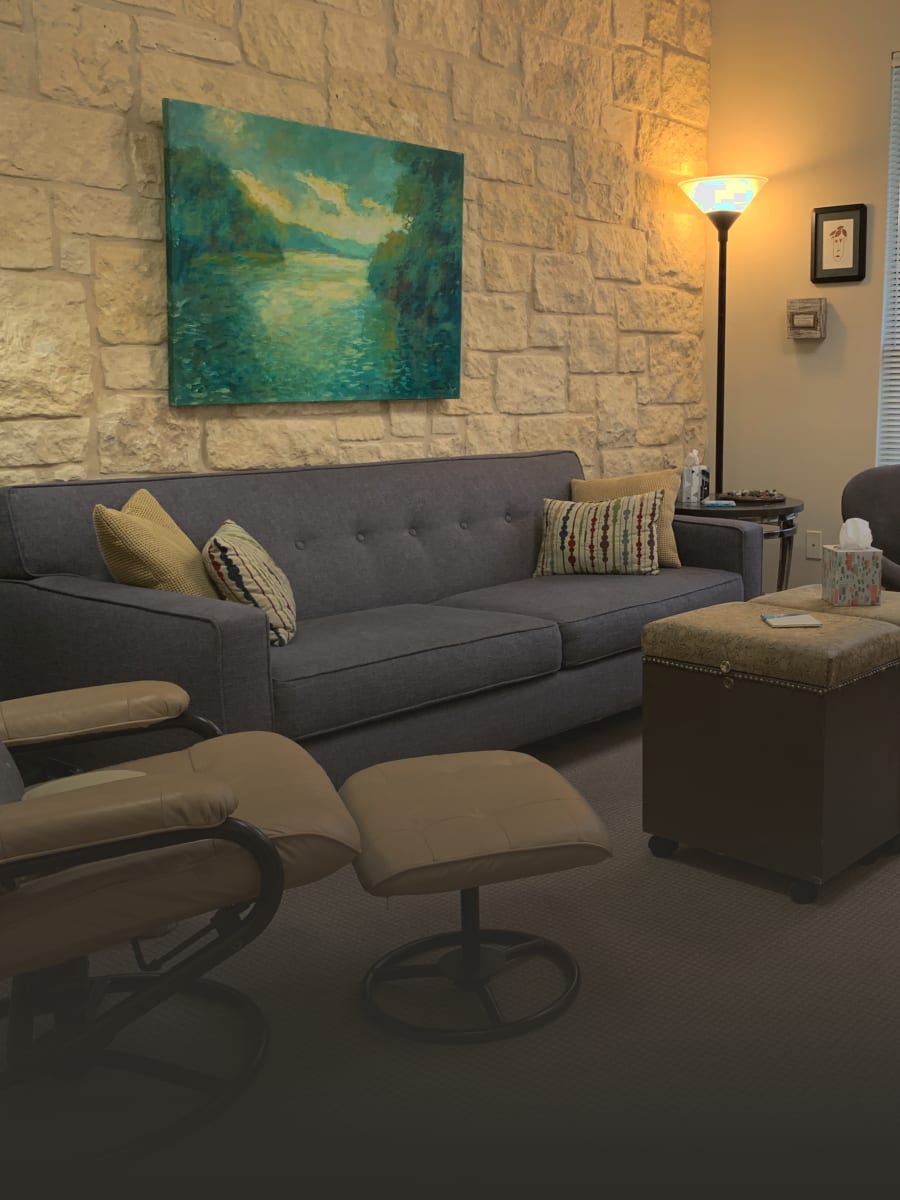 A therapy room at the Austin office with a grey couch and stone wall
