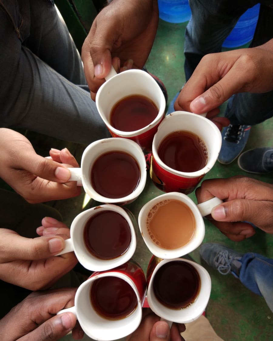Hands from a circle of friends raising mugs of tea and coffee together
