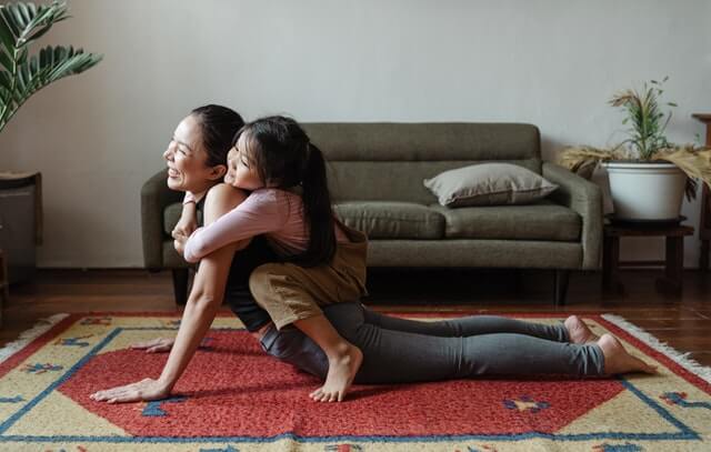 Daughter hugging her mom while doing yoga
