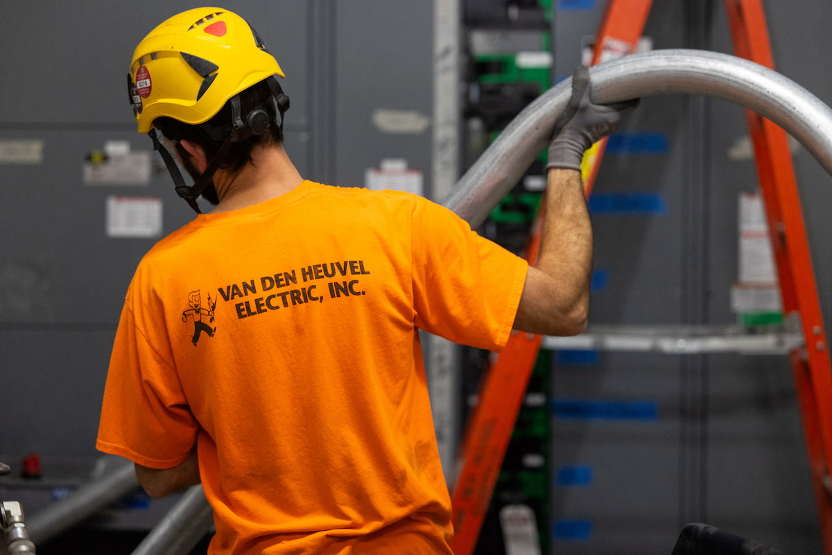 man in orange shirt with hard hart holding pipe