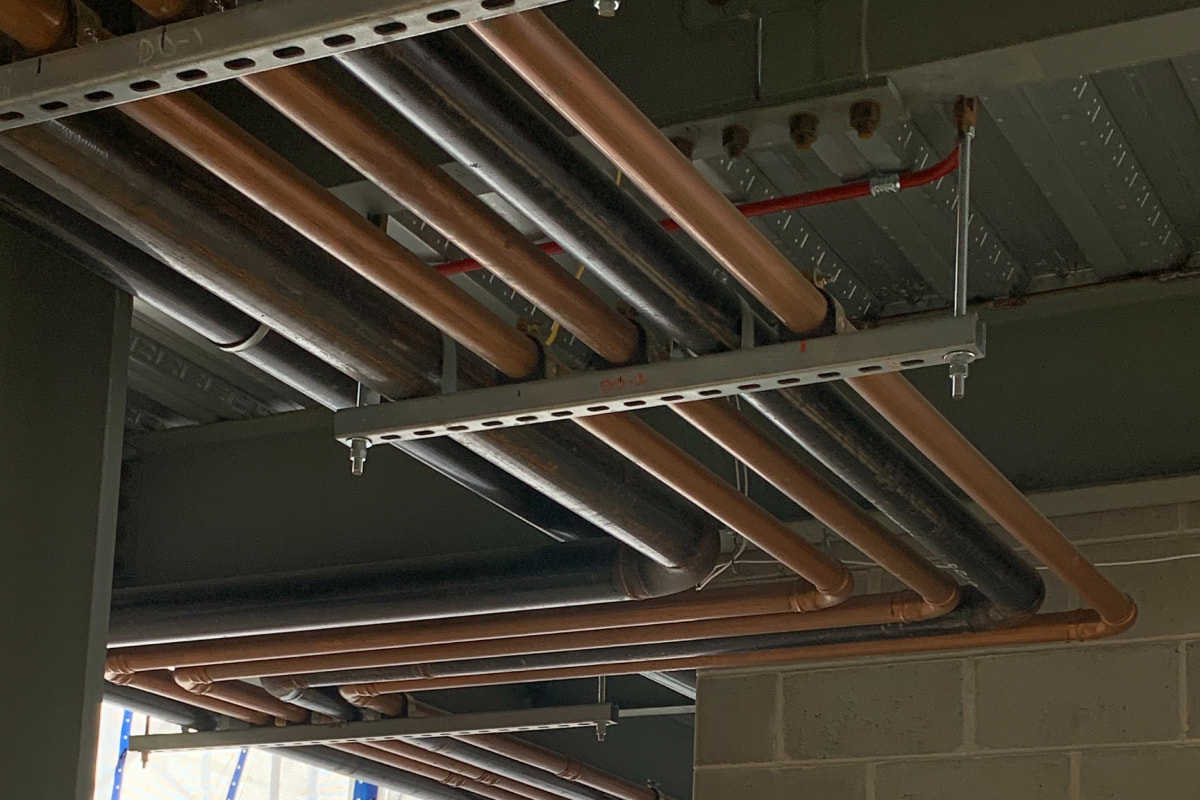 Overhead copper and black iron piping in commercial plumbing repair project in Green Bay, WI.