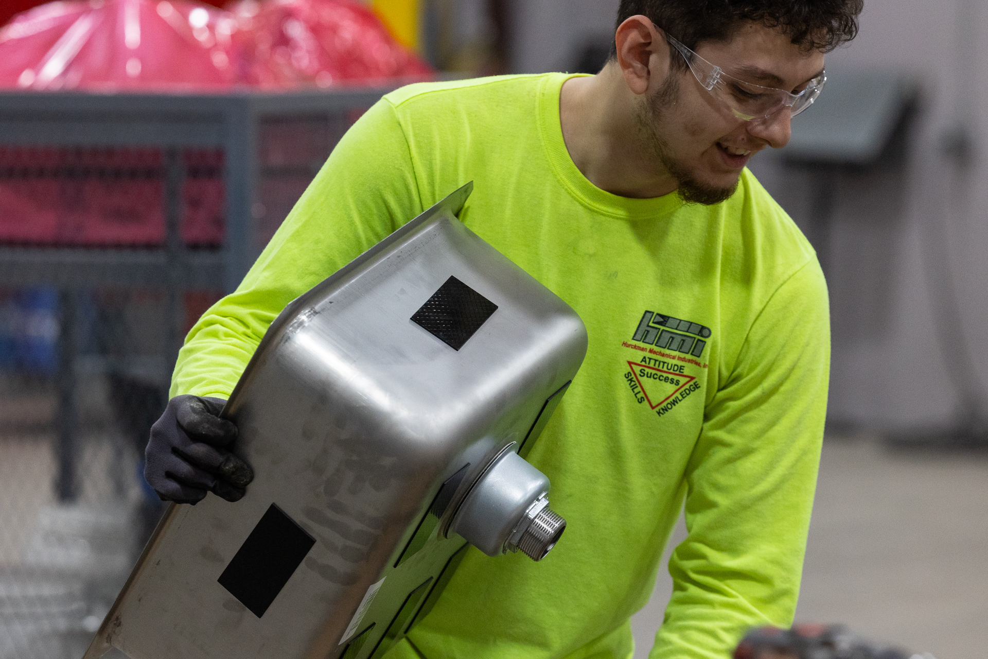Plumbing technician from HMI holding stainless steel sink at fabrication facility in Wausau, WI.