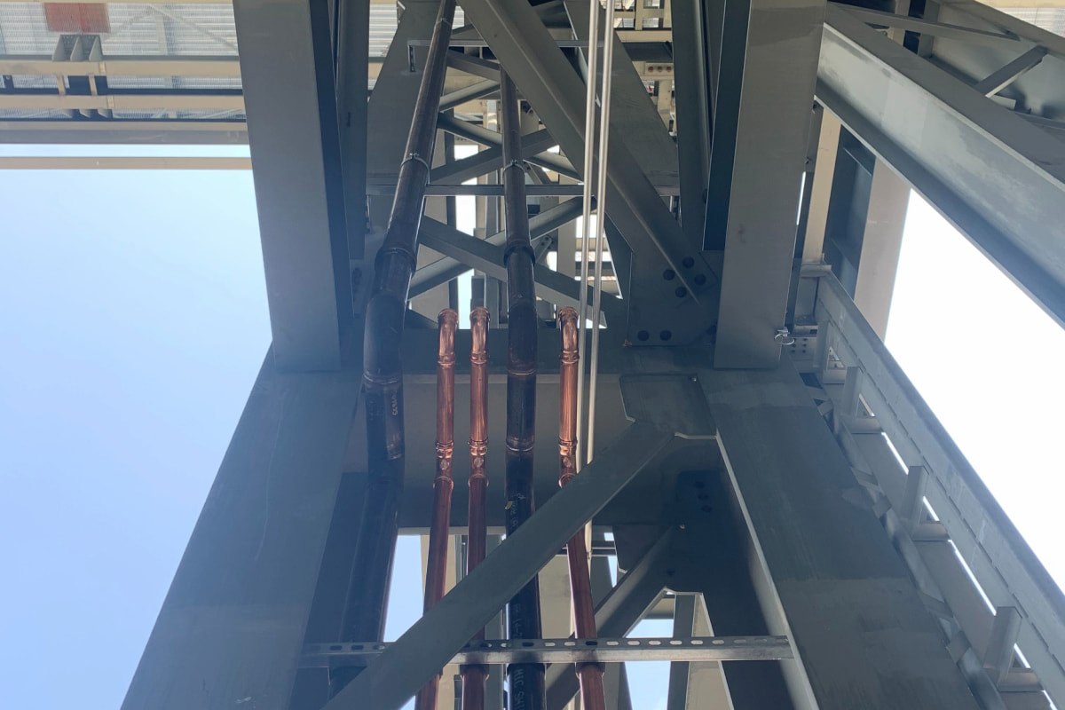 Vertical copper and iron pipe installation through steel frame for commercial plumbing in Green Bay, WI.