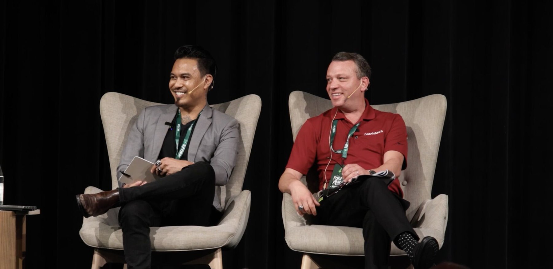 Marco Perrott smiling on stage beside a fellow panelist