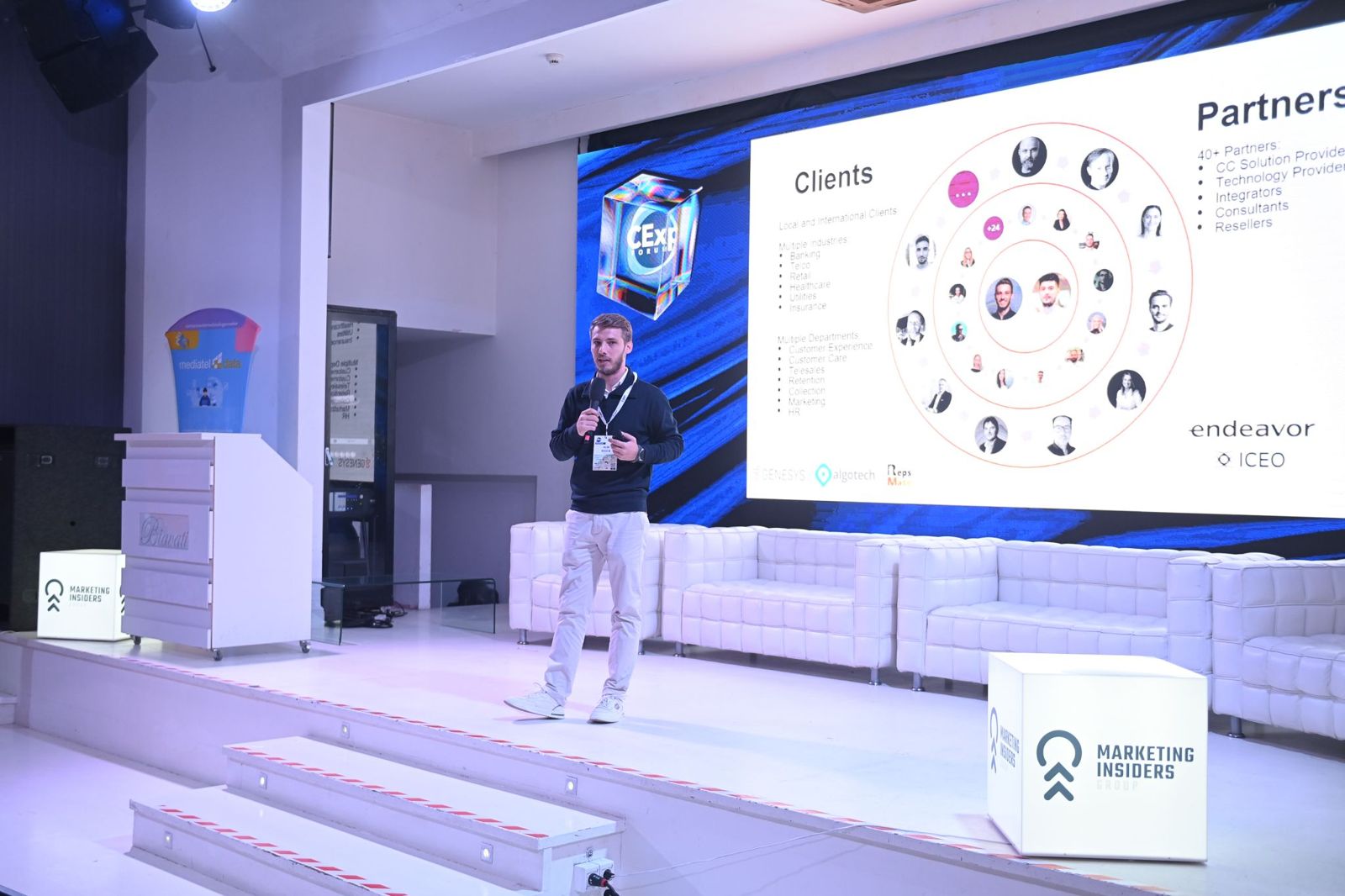 Alin Roșca on stage in front of a screen showing RepsMate's clients and partners